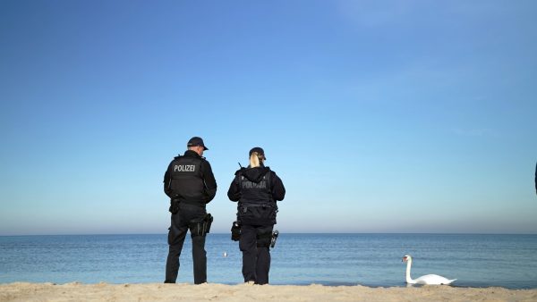 Zwei Polizist:innen des deutsch polnischen Teams am Usedomer Strand. Zwei Polizeibeamt:innen des deutsch polnischen Teams auf Usedom stehen am Strand. Sie stehen mit dem Rücken zur Kamera und schauen aufs Meer.