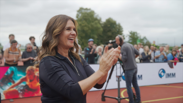 Katarina Witt steht auf dem Sportplatz und applaudiert während der Veranstaltung "Inklusiv gewinnt".